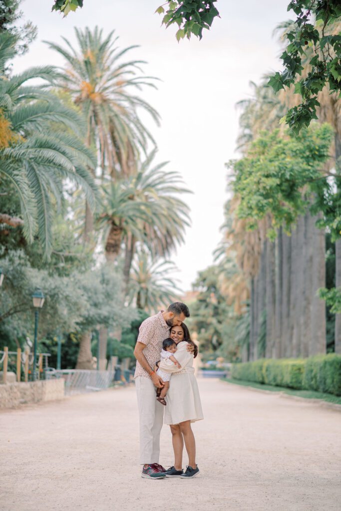 Family walking together beneath the mature trees in Viveros Gardens during a photoshoot in Valencia