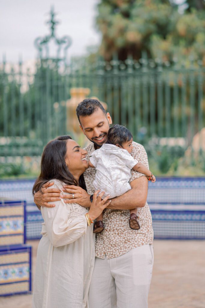 Parents sharing a quiet moment with their baby surrounded by greenery in Jardines del Real in Valencia