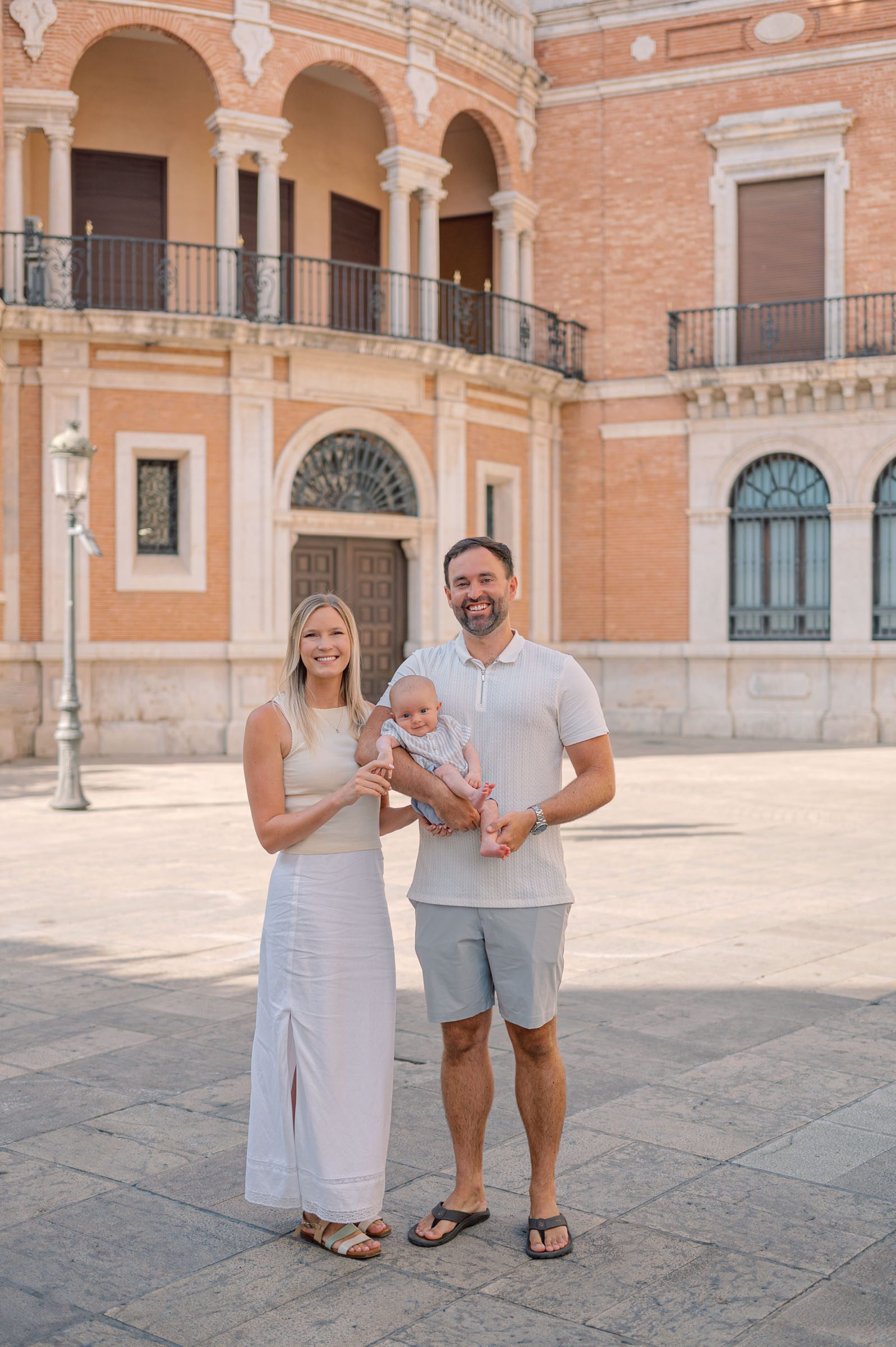 Family of three smiling together near Valencia Cathedral during a morning photoshoot